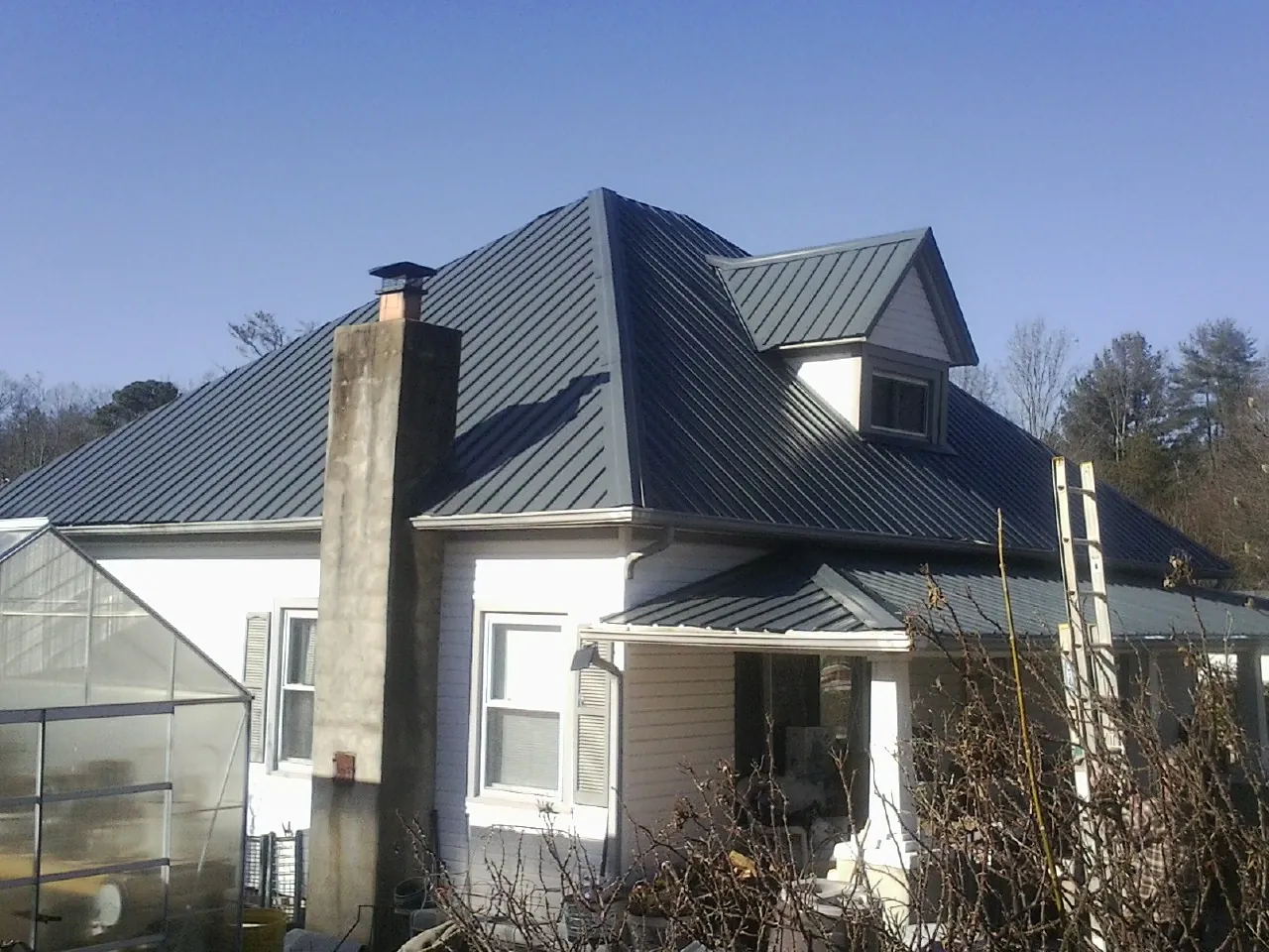 Dark blue standing seam metal roof on a white farmhouse with dormer — Slate & Tile Roof Repair by Roofing Brothers in Huntingburg