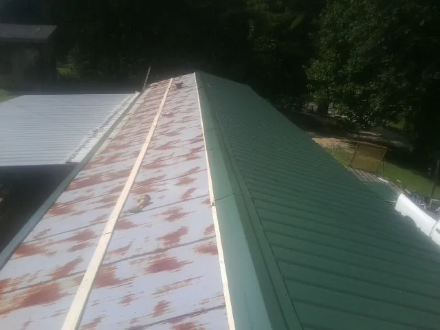 Old rusted panels beside newly installed green metal roofing — Wind Damage Roof Repair by Roofing Brothers in Huntingburg