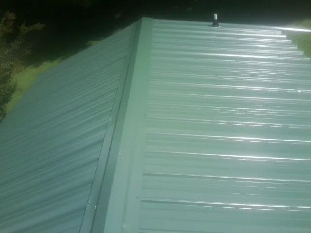 New green metal panels meeting at the ridge of a roof — Flat Roof Repair work by our crew in Huntingburg