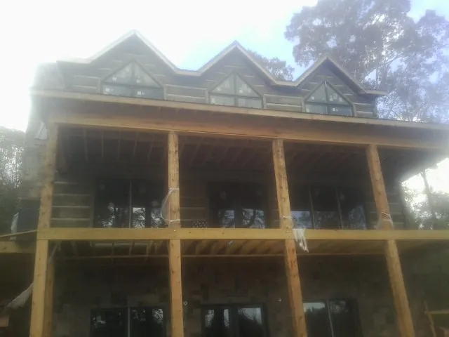 Dormers and porch framing on a large log home under construction — Roof Coating work by our crew in Huntingburg