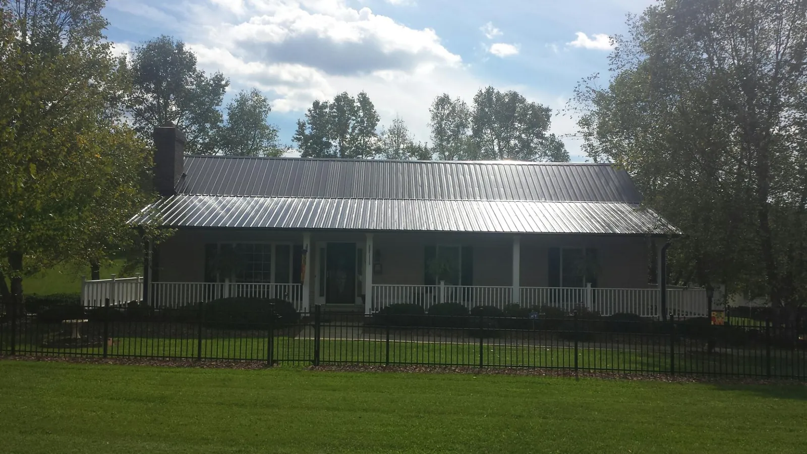 Gray metal roof on a brick ranch with a full width front porch — Gutter Guard Installation work by our crew in Huntingburg