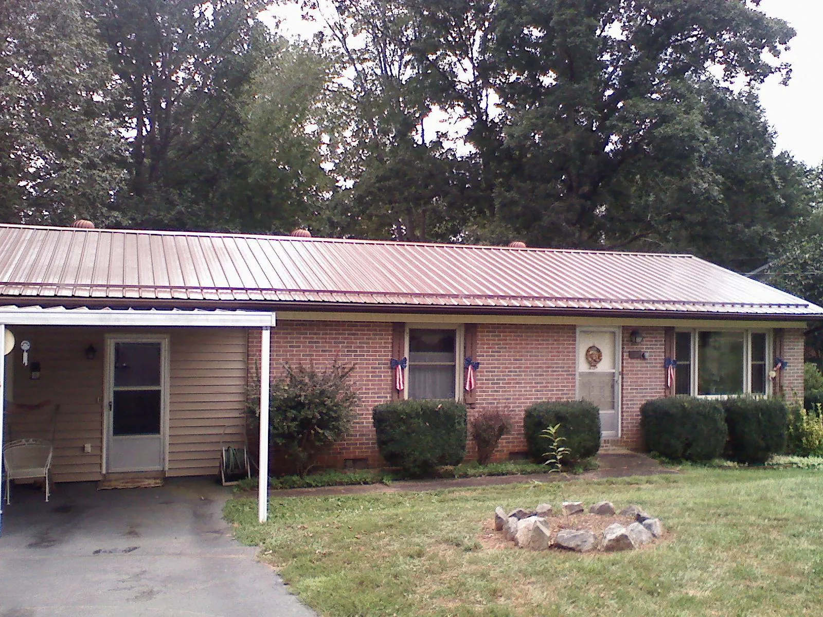 Bronze metal roof and carport on a brick ranch home — Roof Repair work by our crew in Huntingburg