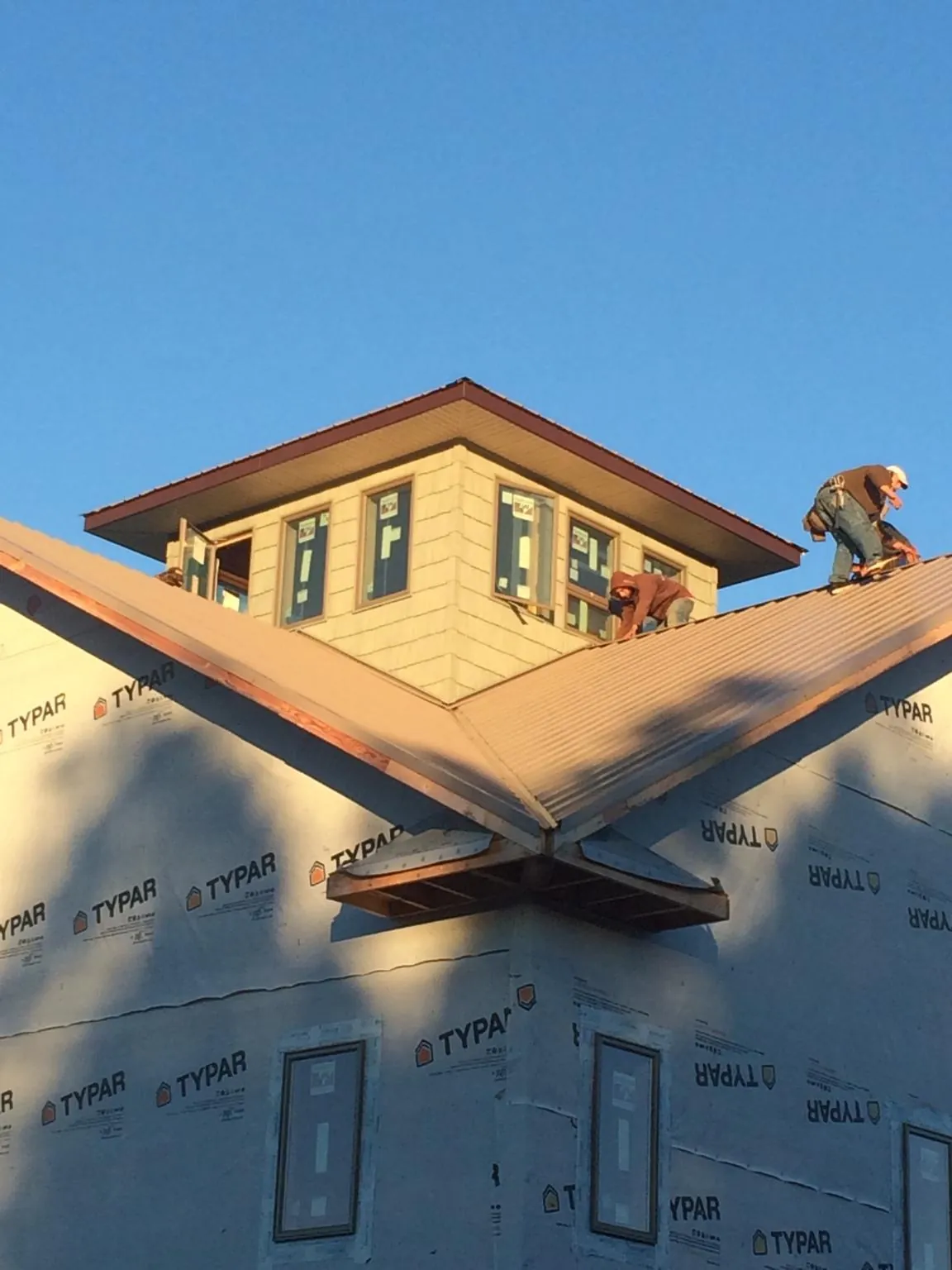 Roofers working around a rooftop cupola on a new metal roof at sunset — Roof Waterproofing in Huntingburg by Roofing Brothers
